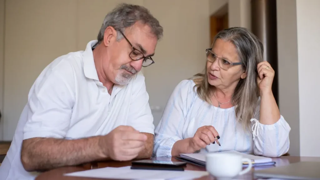 Ouder stel aan tafel berekent samen hoeveel pensioen ze nodig hebben