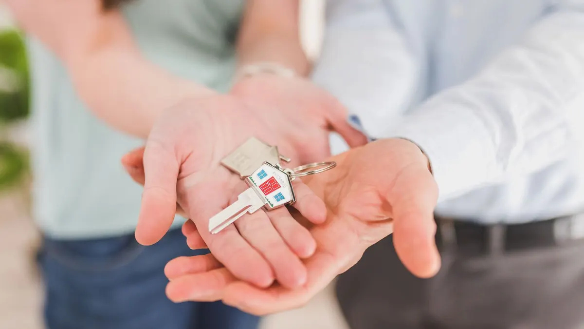 Stel houdt de sleutels van hun nieuwe koophuis vast, klaar om opstalverzekering te regelen