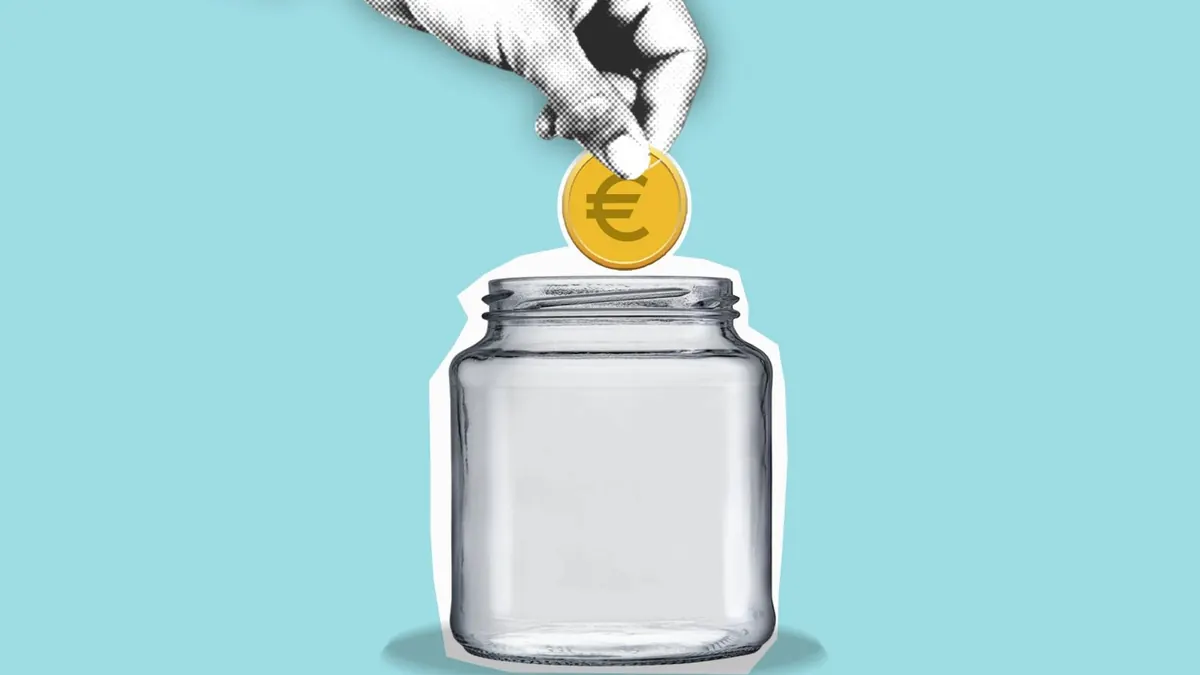 Hand stopt een euromunt in een lege glazen pot als symbool voor zelf pensioen opbouwen
